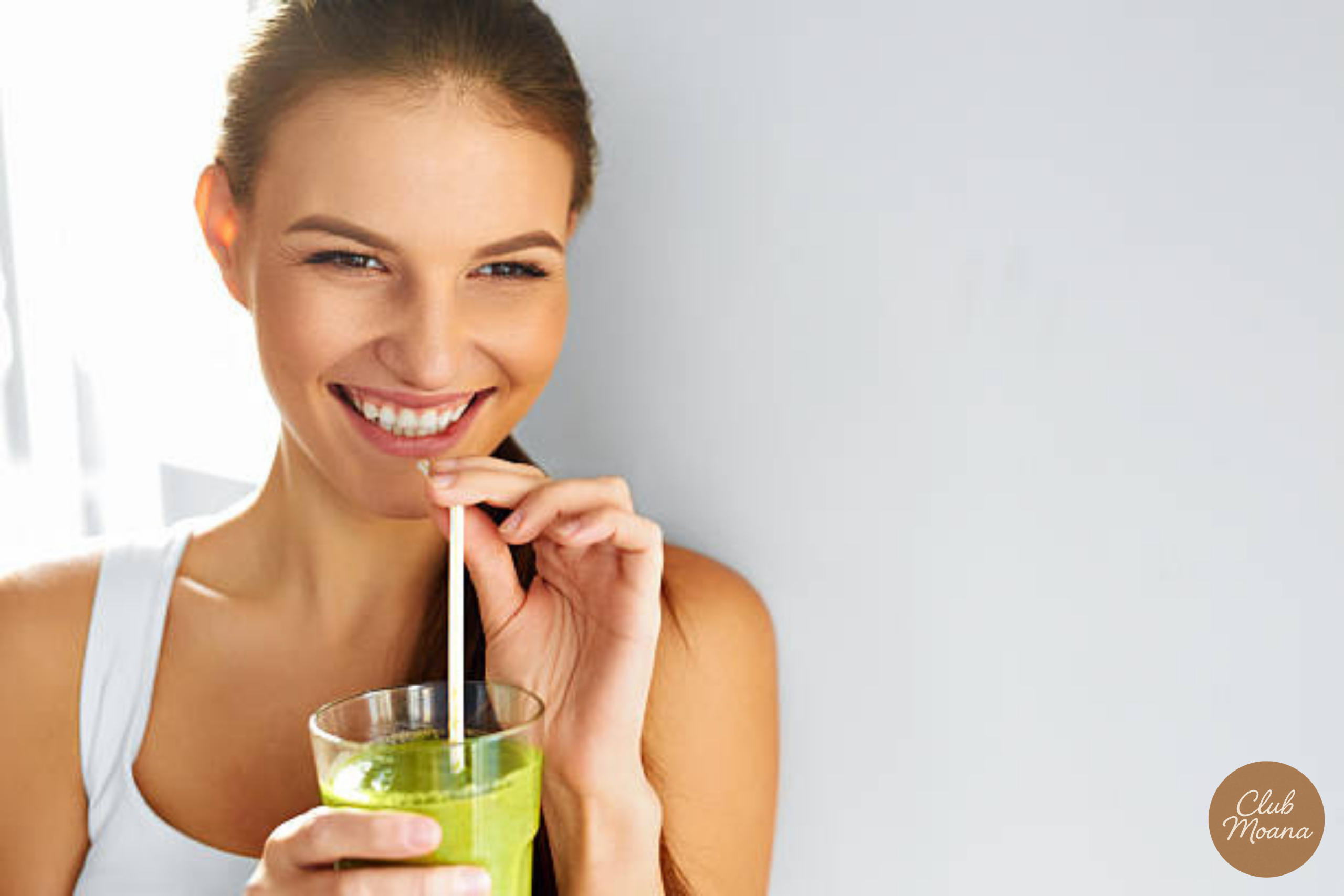 A healthy person drinking a green smoothie or greens powder mixed in water