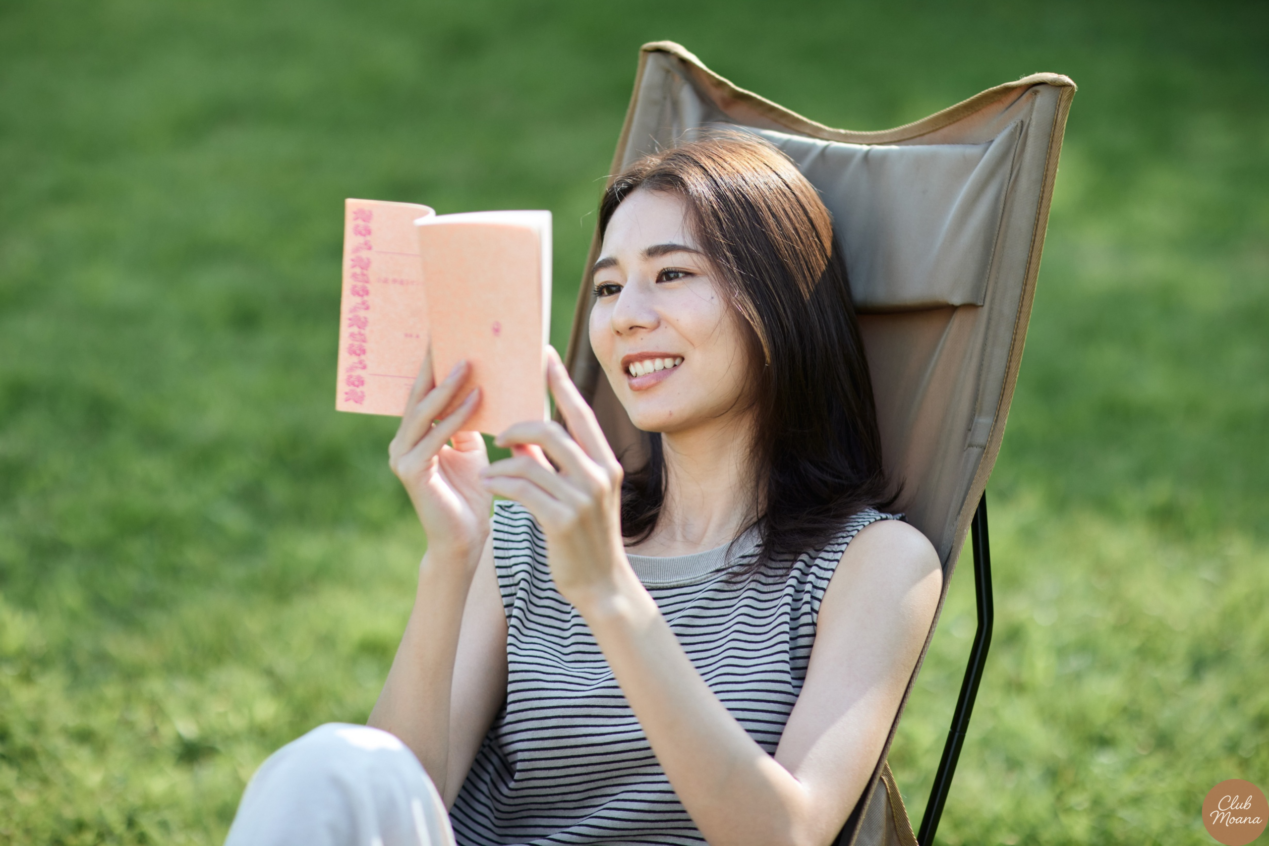 Smiling person enjoying a book outdoors without glasses