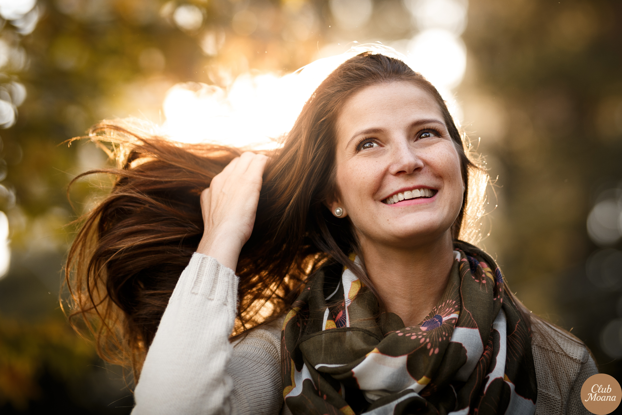 Peaceful woman running fingers through thick, healthy hair in the sunlight